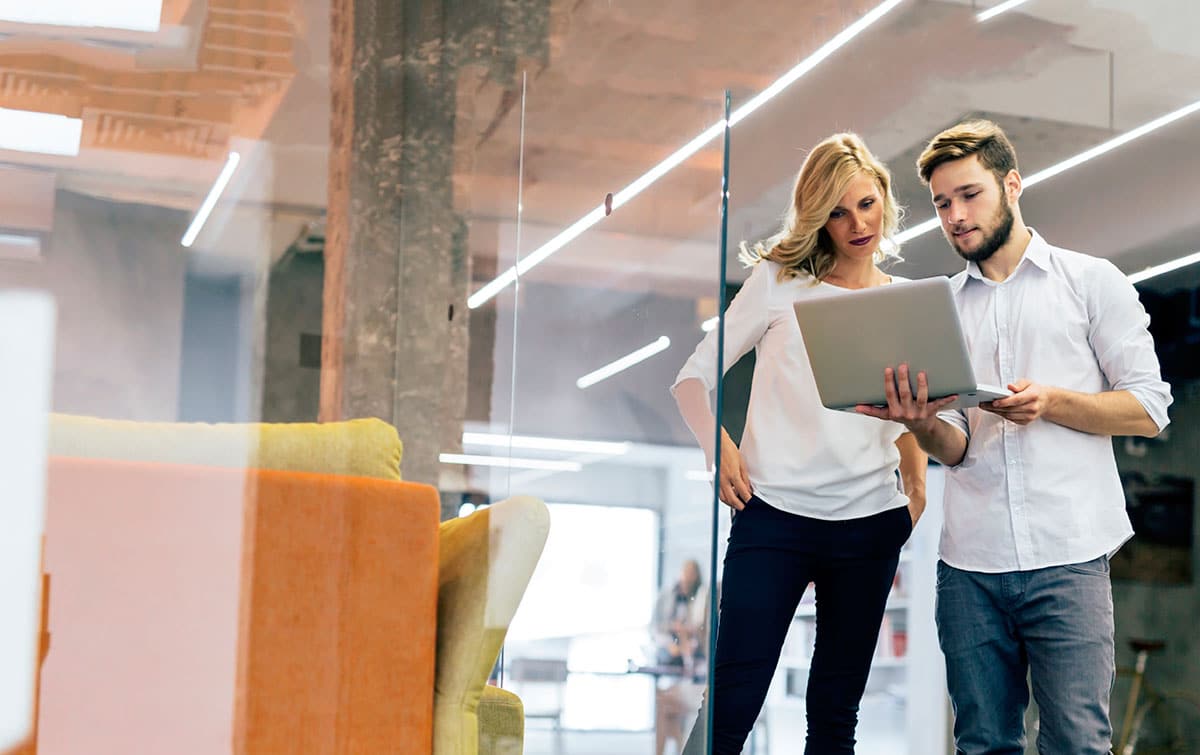 Co-workers looking on a laptop at online courses to boost your skills