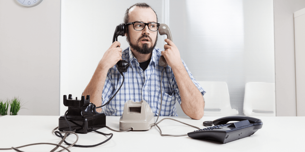 Office worker juggling several phones he looks stressed out