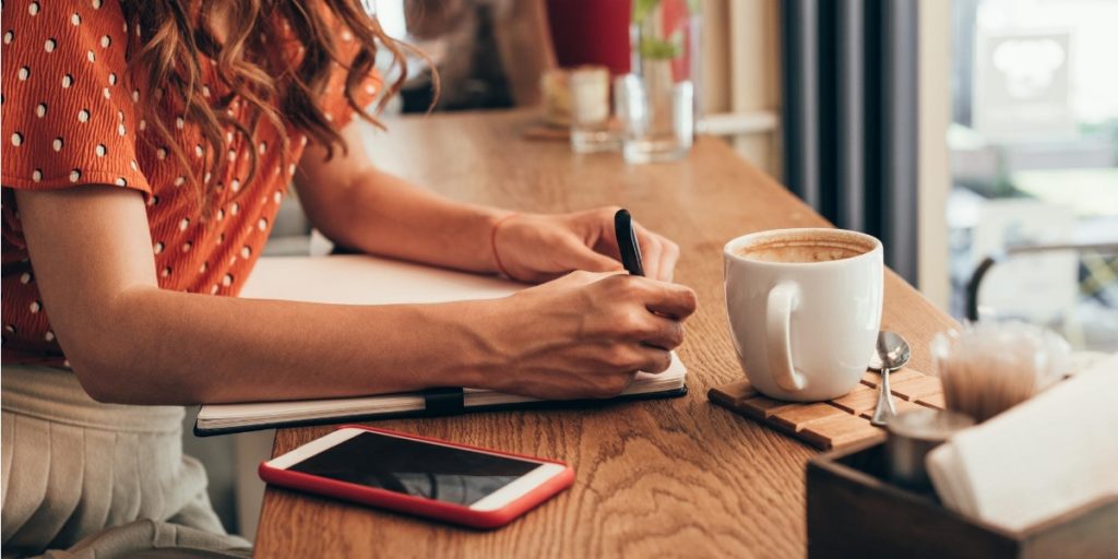 A young lady enjoying a coffee whilst researching a potential employer on social media