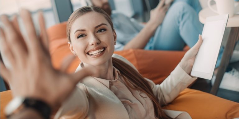 a woman 'hi five' a colleague, looking excited at the possibility of relocating for a job