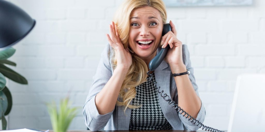 Woman pulling an uncomfortable face as she fears talking on the phone at work