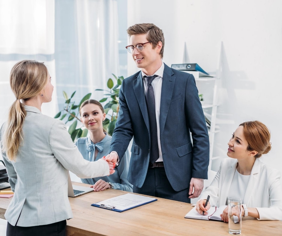 A panel of three interviewers greet their interviewee