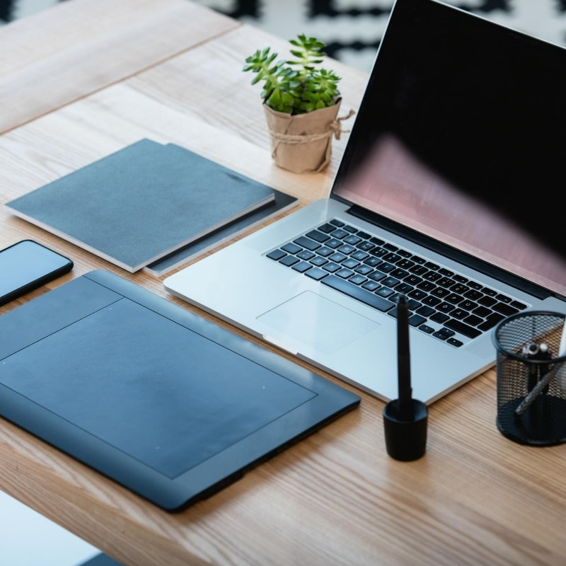 Desk furnished with a laptop, smartphone and graphics tablet. Exactly the kind of technology that a graphic designer might need to work from home