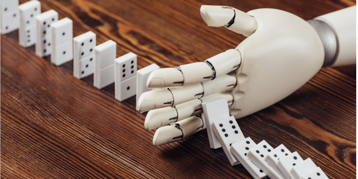 A robot hand stops a sequence of dominoes falling down