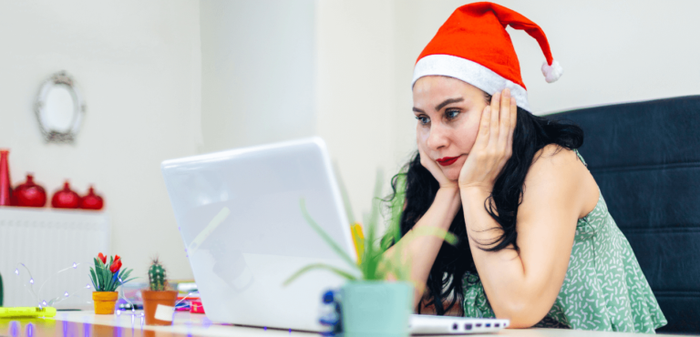 Young lady job hunting at Christmas at her laptop wearing a Santa's hat