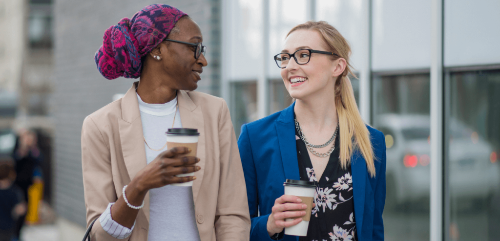 Two ladies enjoying coffee as they walk to work