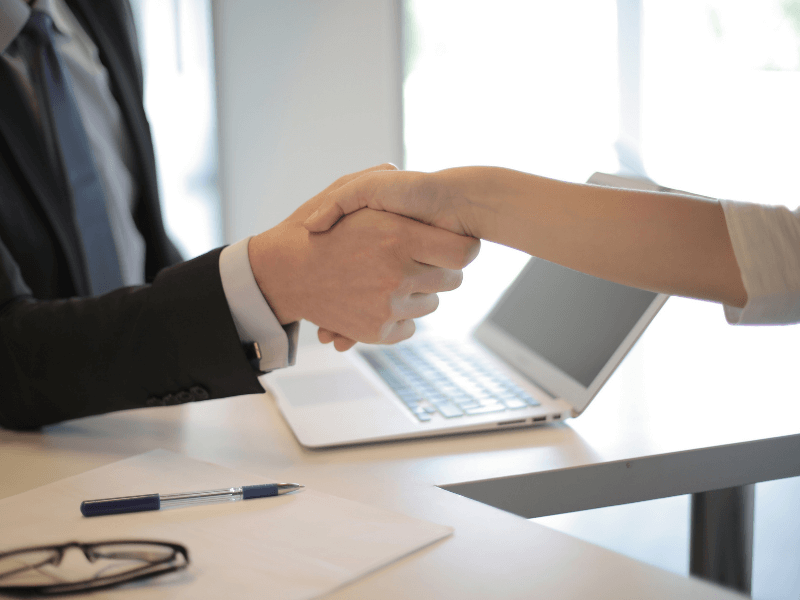 Interviewer successfully hiring tech talent shakes the hand of his new recruit