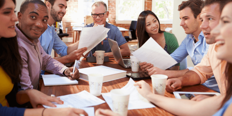 Group of people at work talking and smiling around a table