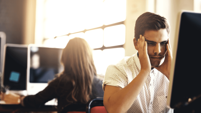 Man wondering how to survive working your notice period sits with his head in his hands at his desk