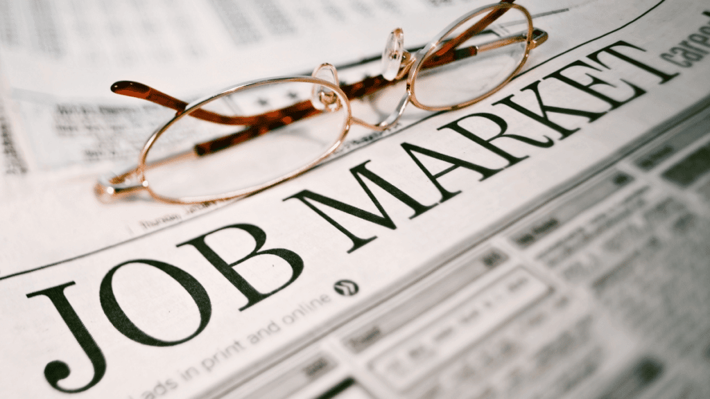 Pair of glasses rest on the jobs market section of a newspaper