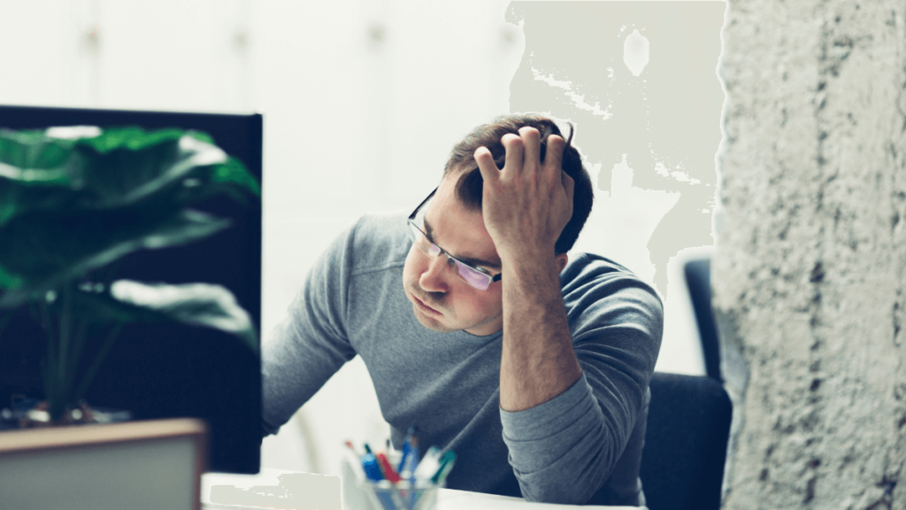 Job applicant looks at computer screen in despair with head in hand.