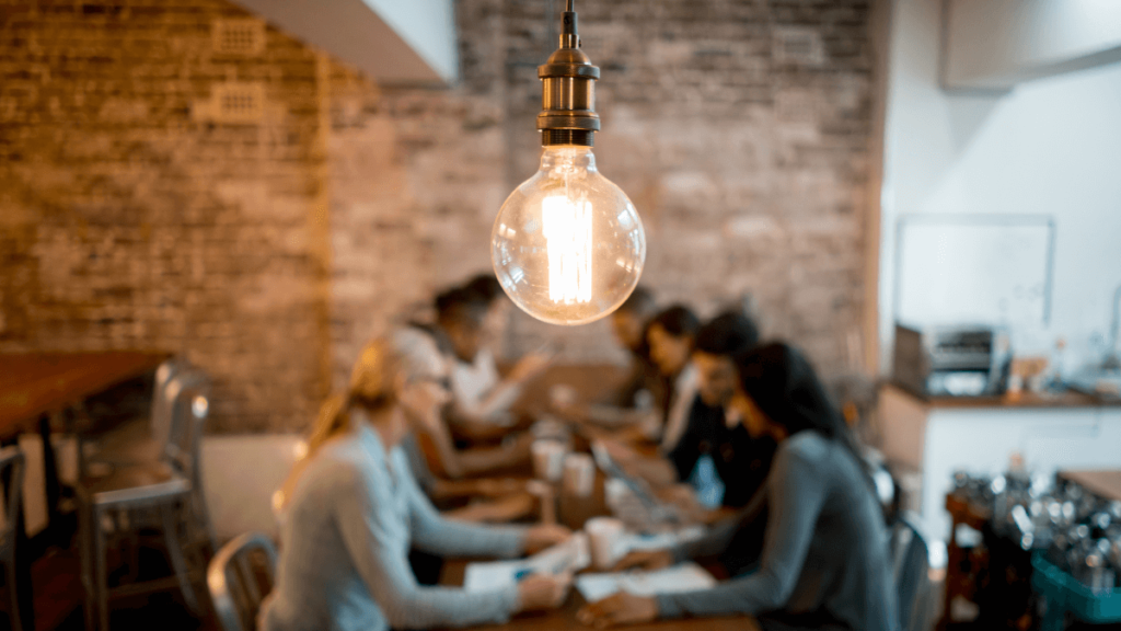 A team of tech workers huddle around a table to generate new ideas