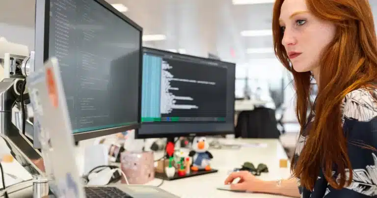 A ginger woman is coding while working in a tech job