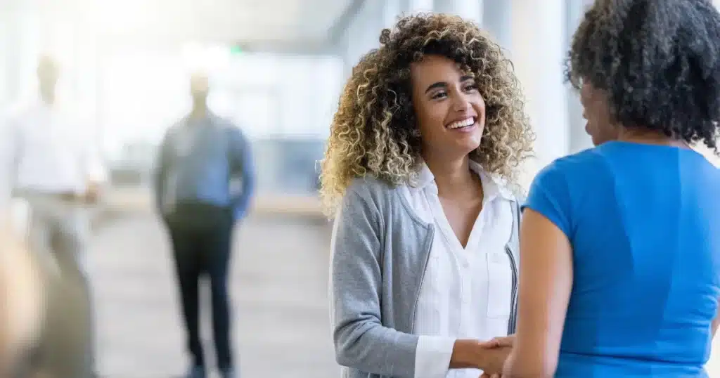 A female hiring manager shakes hands with a happy female candidate after she accepts the job offer