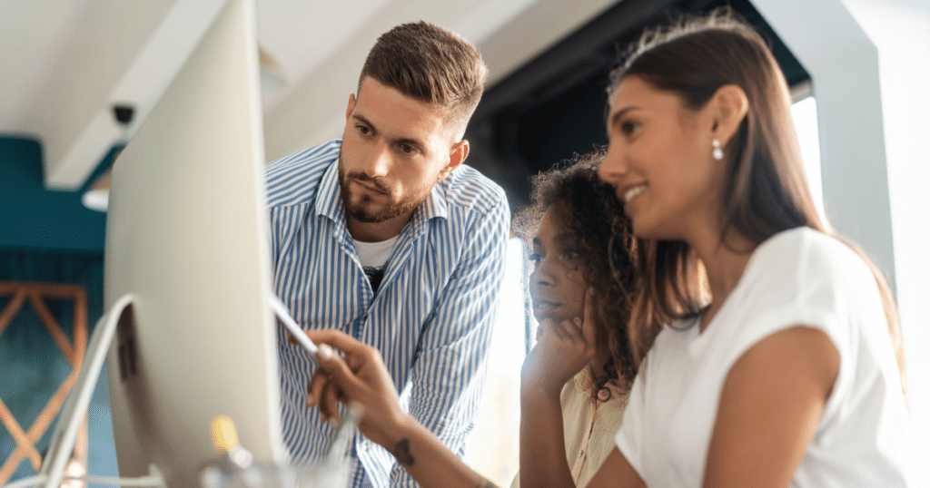 two women and man work together in a computer overseeing a project. Project management is one of the key marketing ecommerce jobs these days