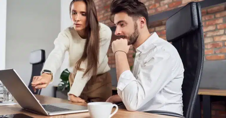 A woman helps a new start learn a work process after he asks her for help