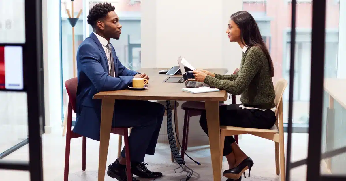 A female hiring manager interviews a male candidate, who wears a smart job interview outfit