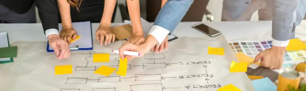 Two women and two men discuss with post-its and documents on a table the budget and timeline of a digital project using Agile methodologies