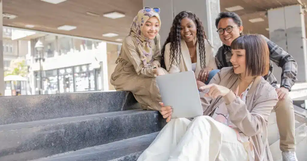 A group of Gen Z young women and young man chat friendly in their break at work