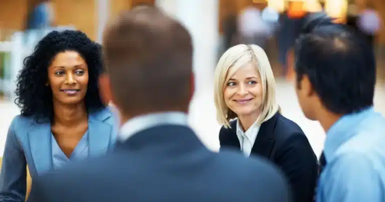 Two woman chat friendly with other team members, looking at the eyes of their interlocutor and smiling