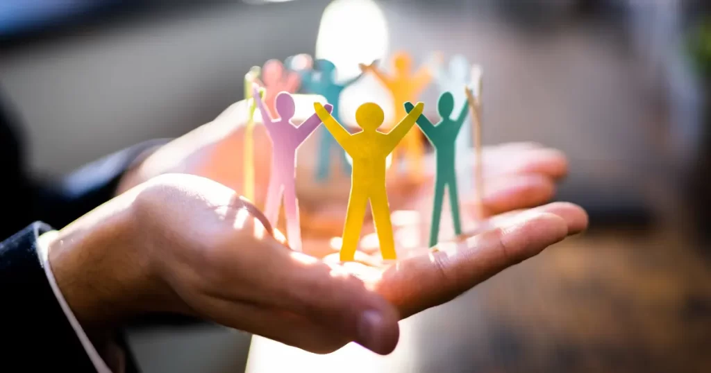 A man holds a paper cut with the shape of diverse human forms to symbolise the diversity of their employer brand